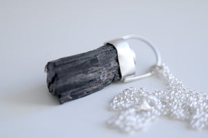 Penjoll de plata amb cristall en brut de Turmalina negra i Turquesa natural.