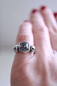 Anell de plata amb Quars amb Turmalina hexagonal i dues Calaveres.